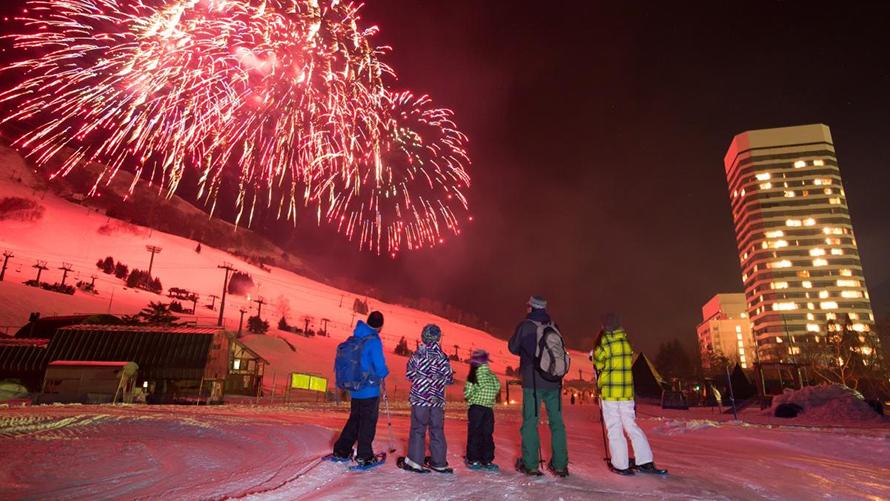ファミリーがゲレンデ打ち上げ花火を見ている