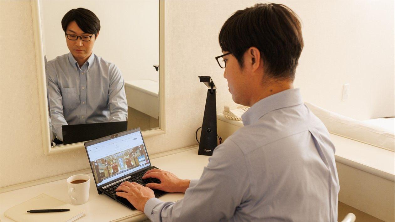 客室内デスクで男性がパソコンを使用する様子