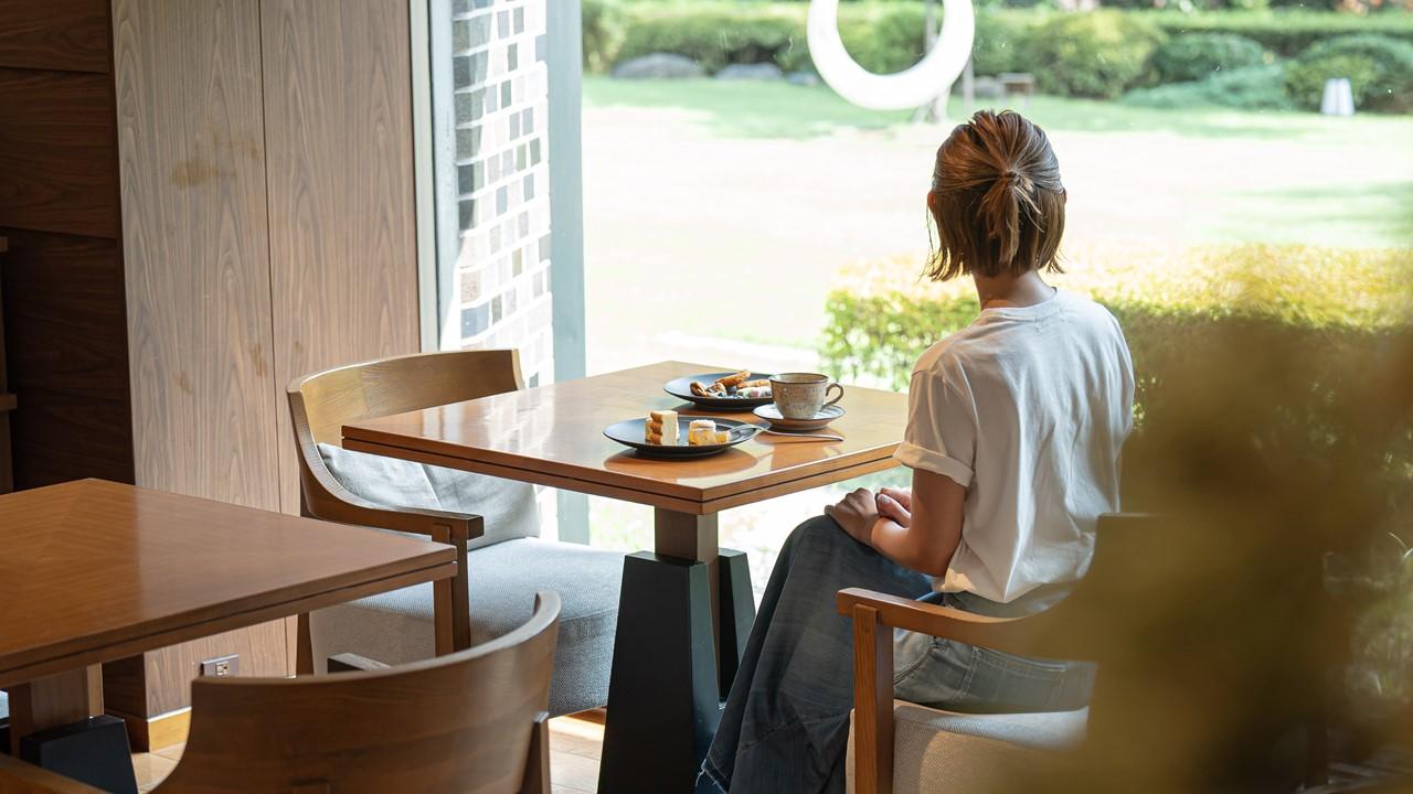 グランドプリンスホテル高輪1Fにある「クラブラウンジ 花雅」で女性が庭園を眺めながら、お茶をしている。