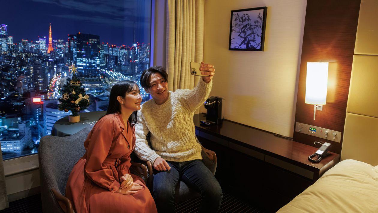 クリスマスルームから望む東京タワーと写真を撮る笑顔のカップル