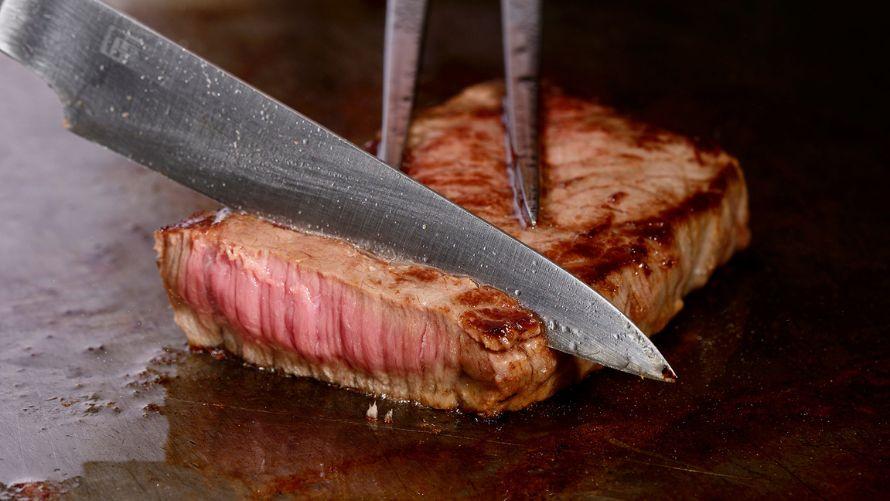 鉄板で美味しそうに焼かれたステーキをカットする様子