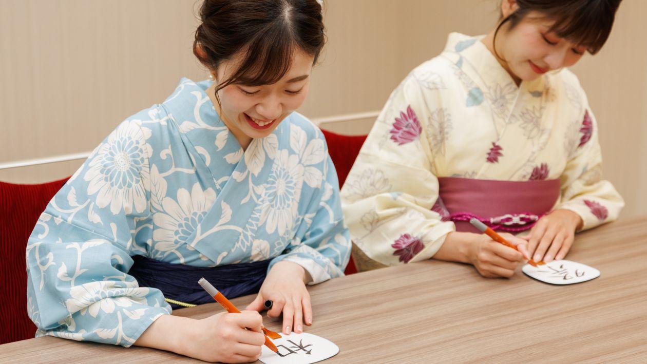 豆うちわに筆ペンで漢字を書く女性たち