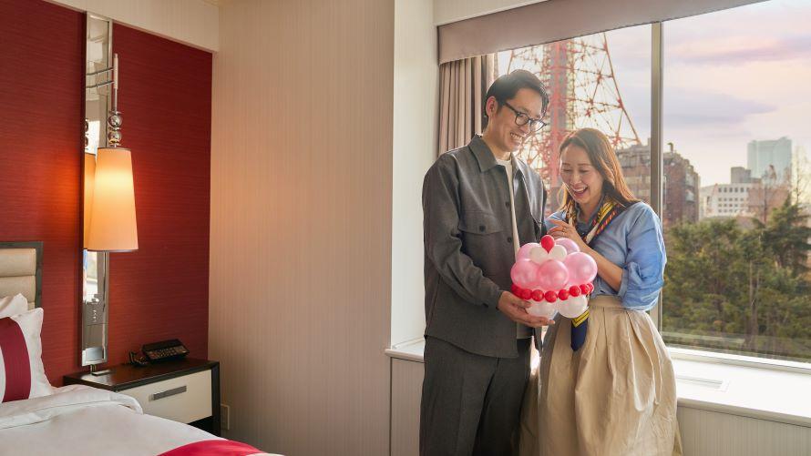 窓辺でデコレーションバルーンを見つめるカップル