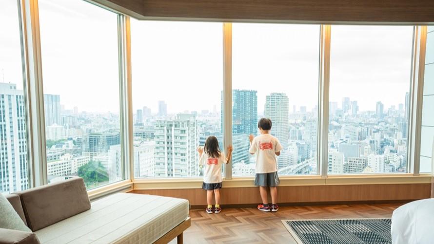窓から東京の街を見下ろす子どもたち。夏の冒険の始まり。