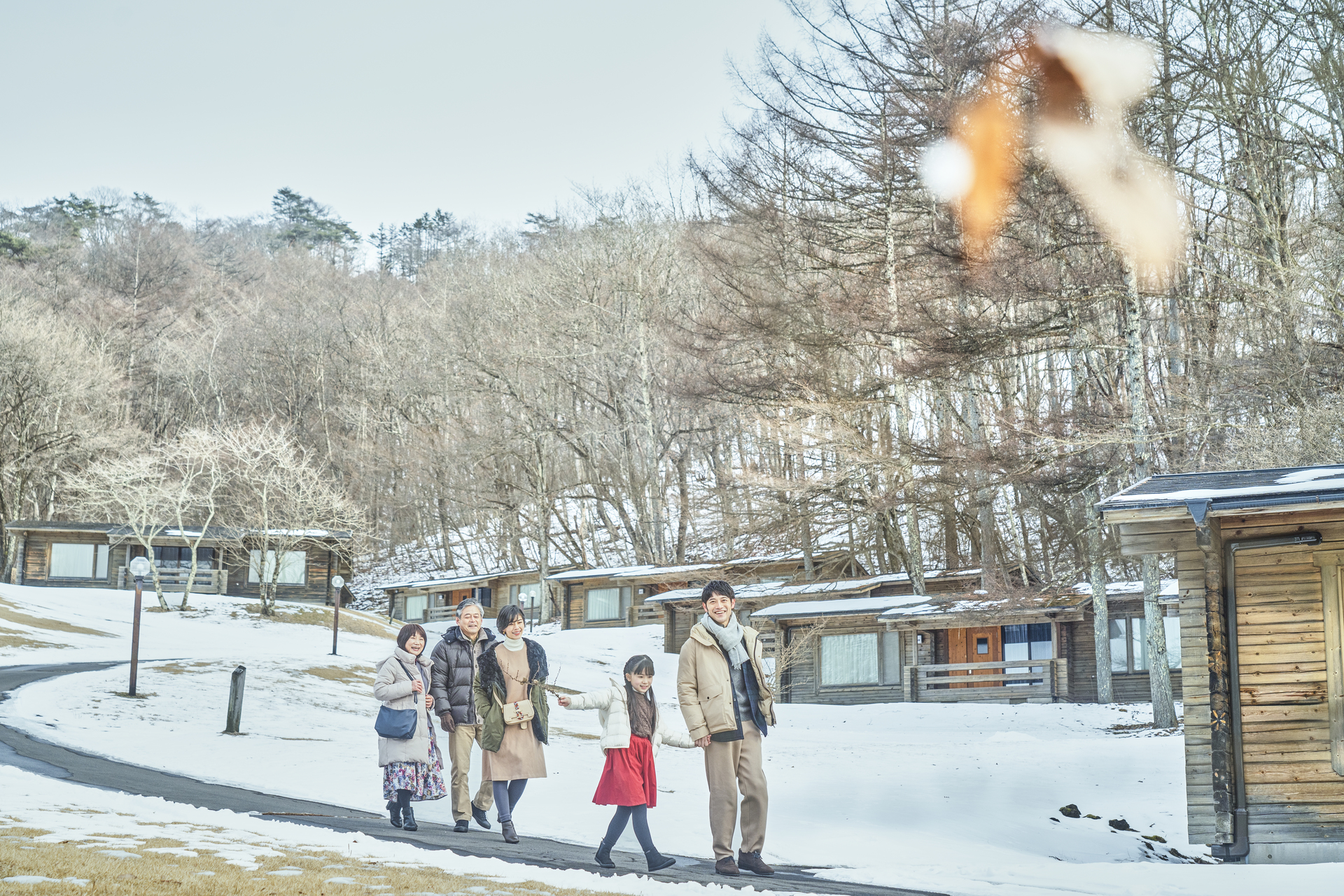 雪景色のコテージまわりを散策する三世代ファミリー