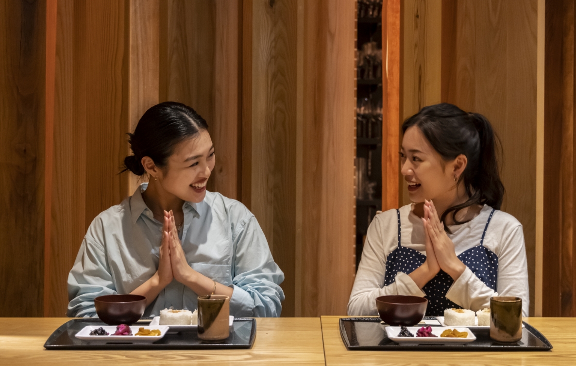 写真：食事前に女性二人が向かい合って手を合わせている様子