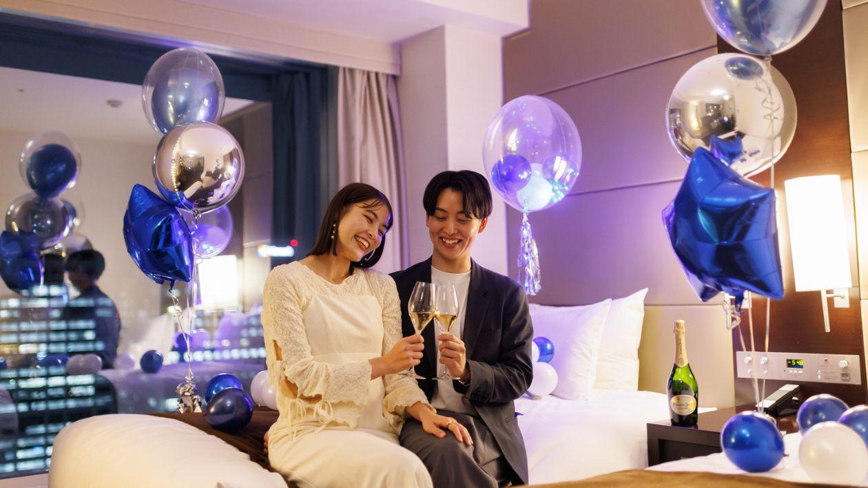 たくさんのバルーンが飾られた部屋で乾杯するふたり