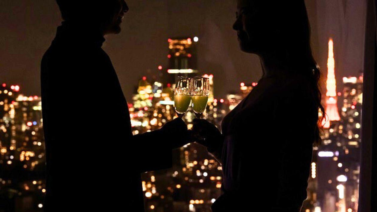部屋から見える夜景を背景に乾杯する二人