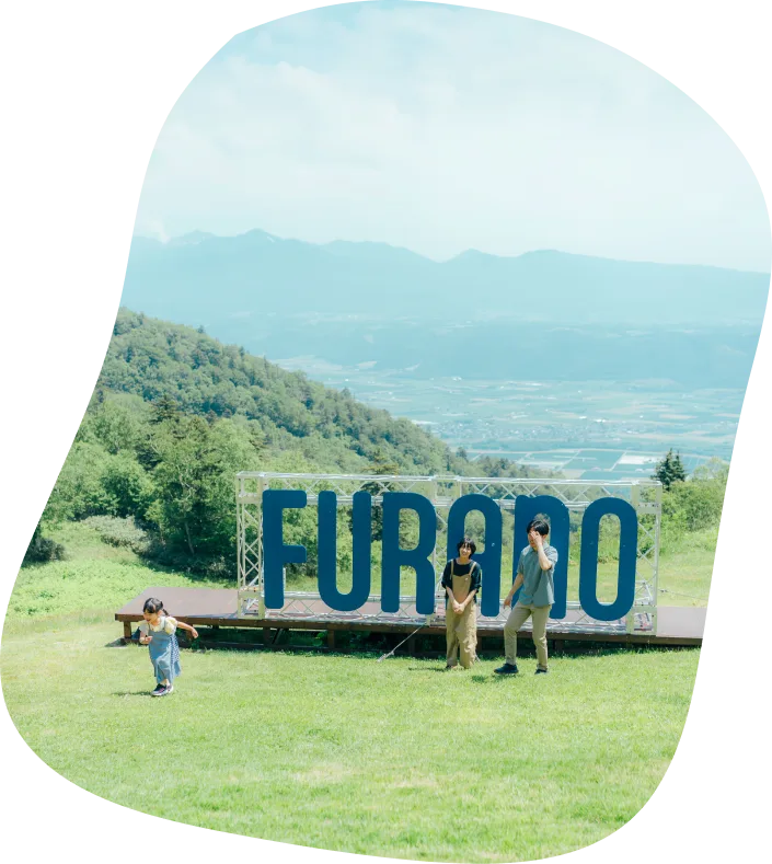 富良野の山頂からの絶景と“FURANO”のオブジェの前で過ごす家族