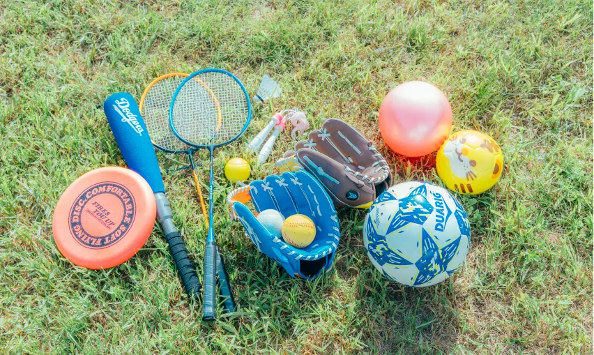 芝生に並んだサッカーボールやグローブなどのスポーツ用品