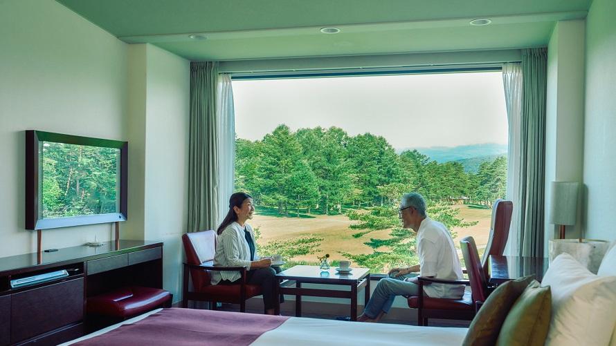客室で語らいあうご夫婦。ピクチャーウインドウの外には軽井沢の自然が広がります。