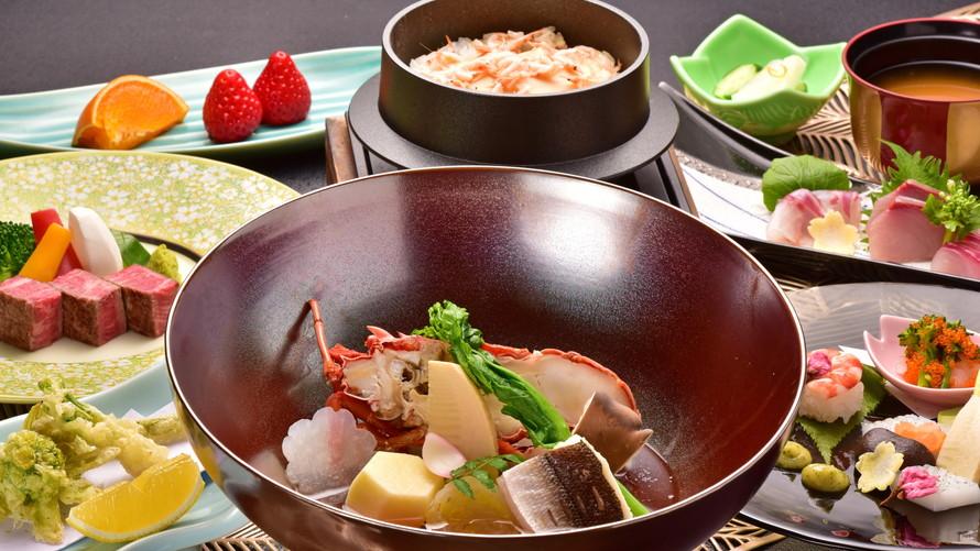  豪華な会席料理の写真です。中央には伊勢海老のような海鮮が、周りにはお肉や旬の食材を使った色とりどりの料理が並んでいます